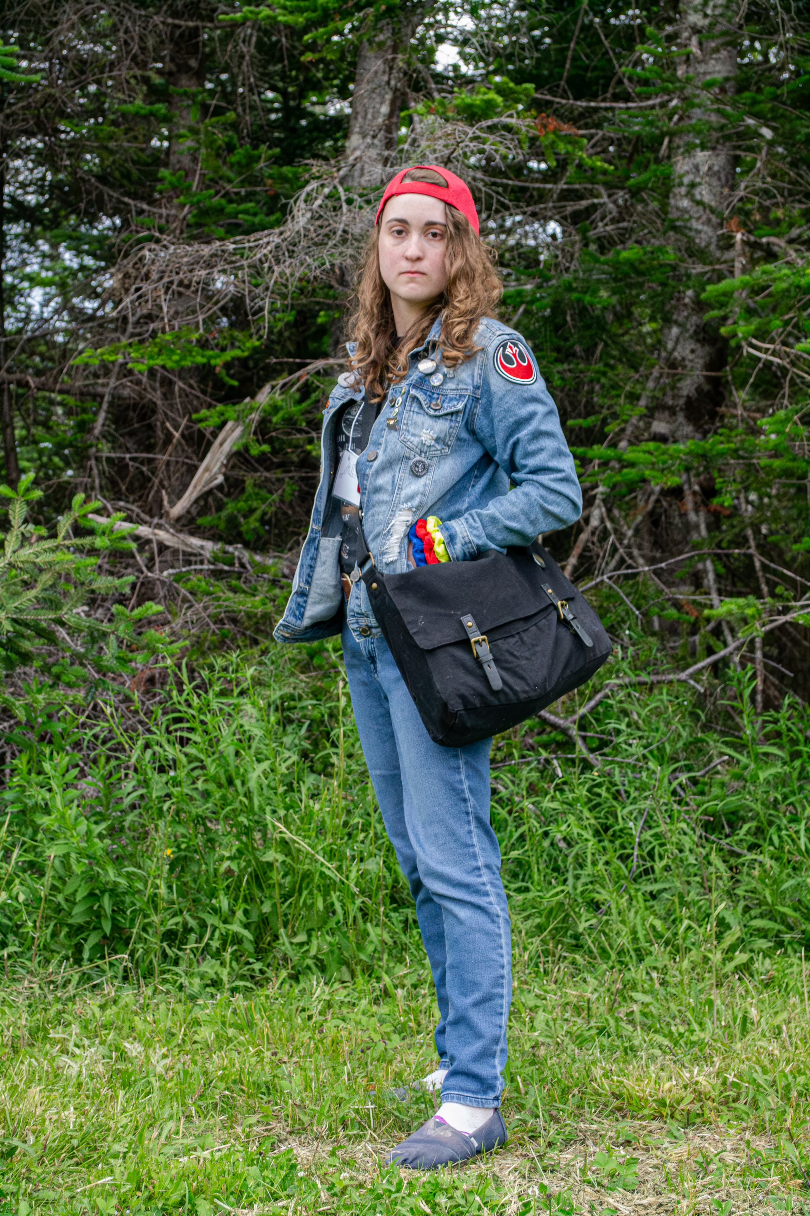 A person wearing an 80's-style vintage outfit posing in front of trees.