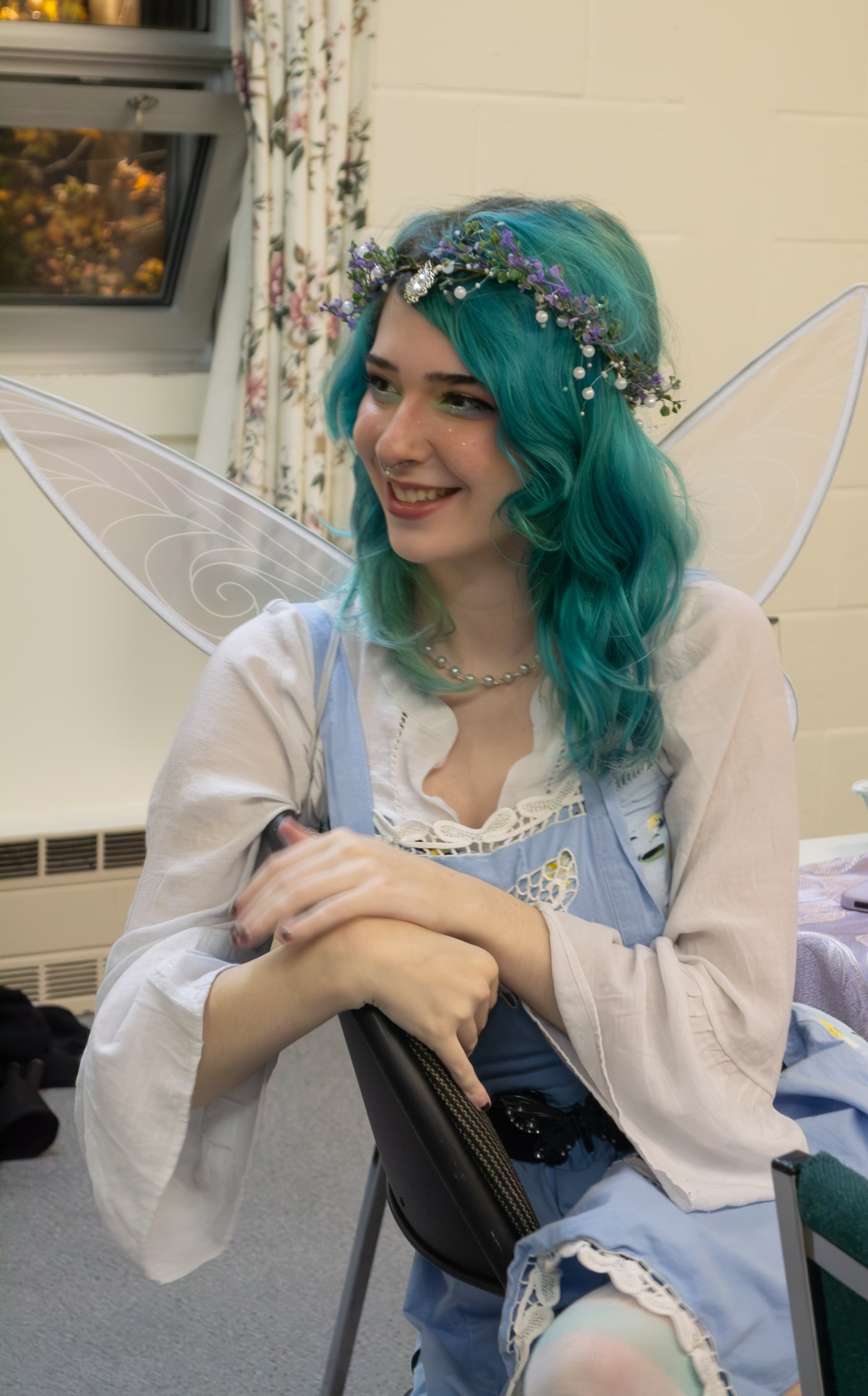 A person wearing a fairy costume smiling at someone off-camera.